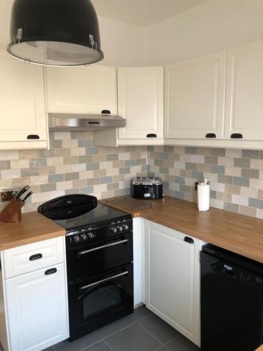 a kitchen with white cabinets and a black stove at Quarry Cottage near Hawes, Yorkshire Dales, Pet free in Hawes