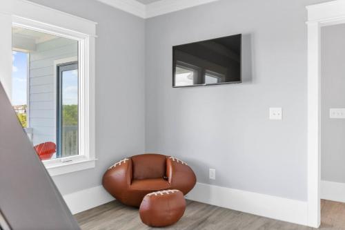 a living room with a leather chair and a flat screen tv at Dune Our Thing North Topsail Beach in North Topsail Beach
