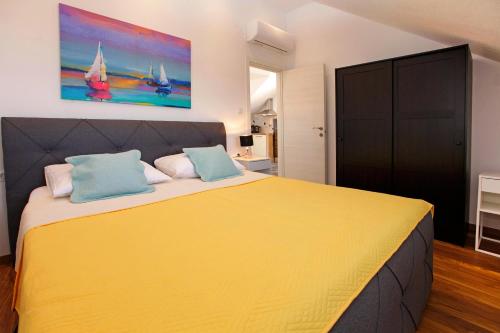 a bedroom with a large yellow bed with blue pillows at Penthouse Vanja in Bol