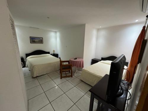 a hotel room with two beds and a flat screen tv at Hotel y Restaurante Costa del Sol in Mata de Limón