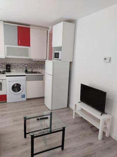 cocina con electrodomésticos blancos y TV. en Loft Albergueria, en Zamora