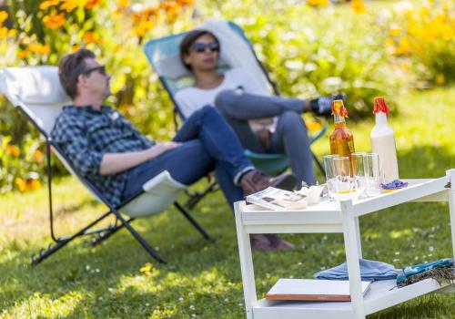 two people sitting in chairs in a yard with a table at Plaine et Colline Chambres et table d'hôtes Isère in Gillonnay