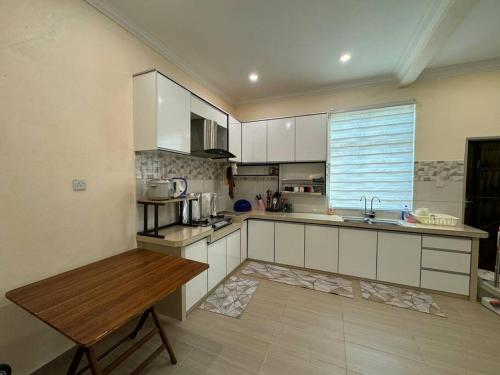 a kitchen with white cabinets and a wooden table at Homestay Bagan Serai in Bagan Serai