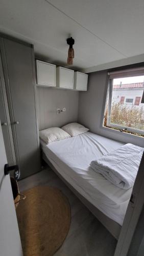 a small bedroom with two beds and a window at Chalet Joy aan Zee in Hollum