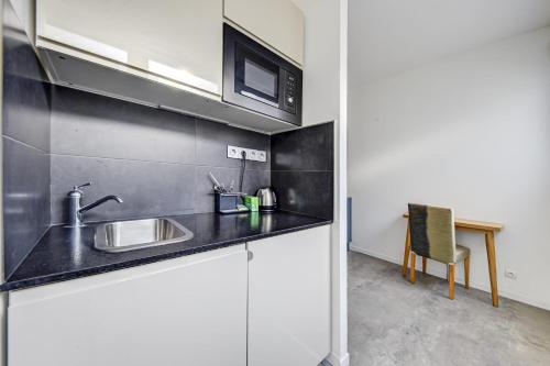 une cuisine avec un évier et un micro-ondes dans l'établissement Lovely studio for 2 near the Seine, à Paris