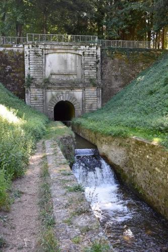 un tunnel de pierre avec un pont sur une rivière dans l'établissement Maison de village, à Les Cammazes