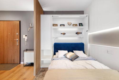 sypialnia z łóżkiem z niebieskim zagłówkiem w obiekcie Unique Apartments - Angielska Grobla w Gdańsku