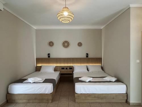 a bedroom with two beds and a chandelier at ANNA ROOMS (Villa Anna) in Nea Vrasna