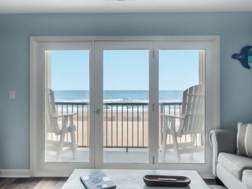 a living room with sliding glass doors with a view of the ocean at Love & Memories in North Topsail Beach