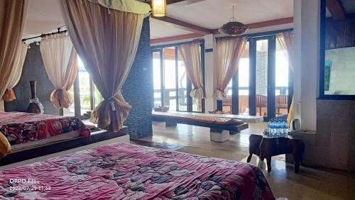 a bedroom with a bed and a table and windows at Rara Villas Lombok in Senggigi 
