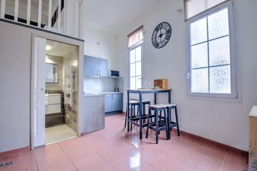 une cuisine avec tabourets et horloge sur le mur dans l'établissement Nid douillet, à Périgueux