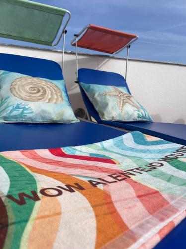 a bed and two chairs with a colorful quilt at Sunset Beach House in Zambujeira do Mar