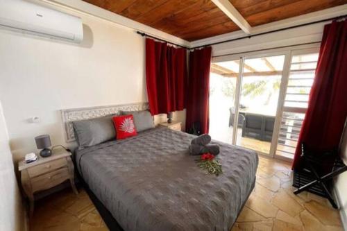 a bedroom with a large bed with red curtains at Enoha Lodge - Climatisation, Fibre, Accès Plage, Parking Privé in Haapiti