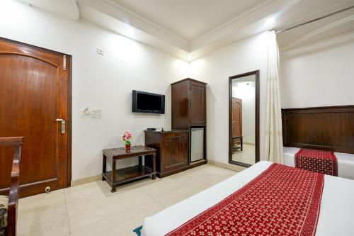 a bedroom with a bed and a tv and a mirror at Hotel Legend International -Just a min walk from New Delhi Railway Station in New Delhi