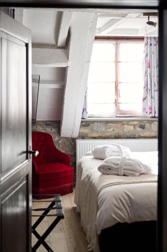 a bedroom with two beds and a red chair at Hotel La Malle Poste in Rochefort
