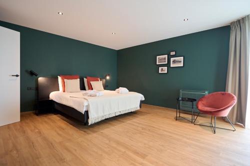 a bedroom with a bed and a red chair at Hotel La Malle Poste in Rochefort