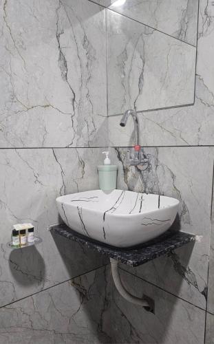 a bathroom with a white sink on a marble wall at Hotel SERENE STAY in Surat