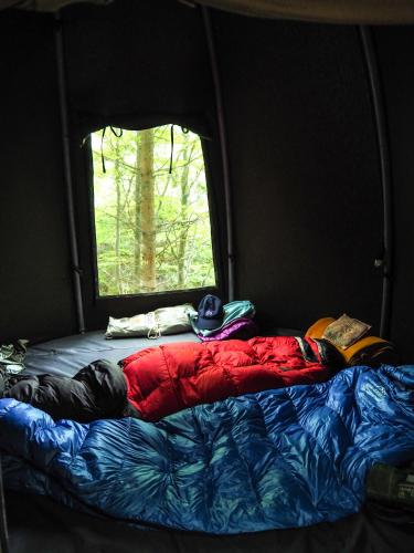 a person laying on a bed in a tent at WisiLas Nad Sercowym Potokiem in Rabka-Zdrój