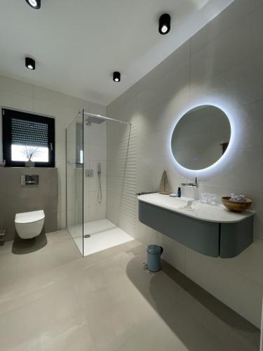 a bathroom with a sink and a toilet and a mirror at Villa Aurea Apartments de Luxe Malinska Luxus Apartments mit beheiztem Pool Insel Krk in Malinska