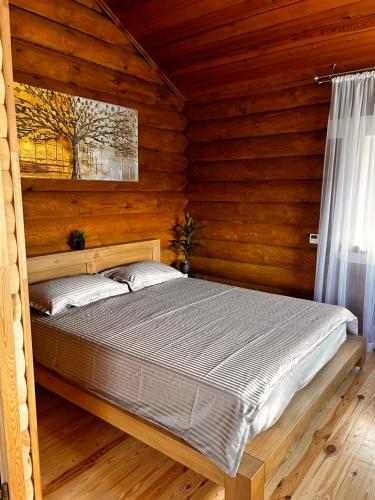 ein Schlafzimmer mit einem Bett in einer Holzhütte in der Unterkunft Pavasario Namai & SPA in Butrimiškiai