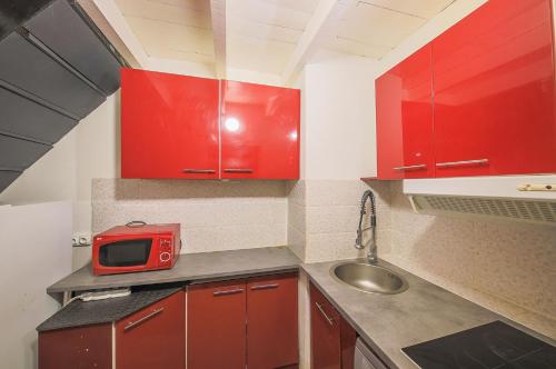 a small kitchen with red cabinets and a microwave at Appart Casamozza Corsica in Lucciana