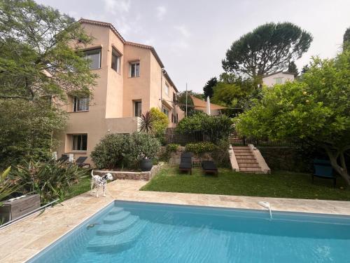 un chien debout à côté d'une piscine en face d'une maison dans l'établissement Bel appartement 4 pièces cosy, à Cannes
