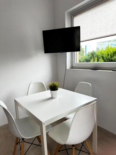 a white dining room table with white chairs and a flat screen tv at Apartamenty Marina in Rowy