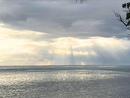 a rainbow in the sky over the ocean at Raihau Lodge - Climatisation, Fibre, Accès Plage, Parking Privé in Haapiti