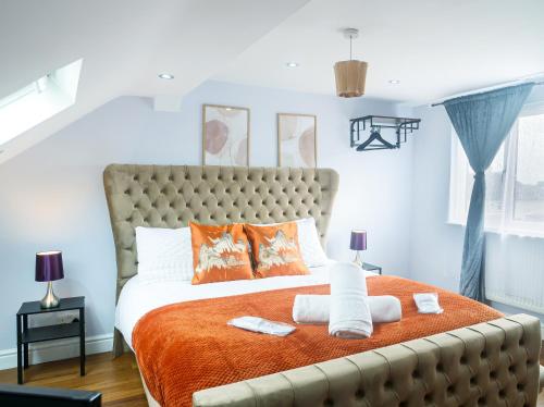 a bedroom with a large bed with an orange blanket at Royal Luxe 6 Bed House in London in Bexleyheath