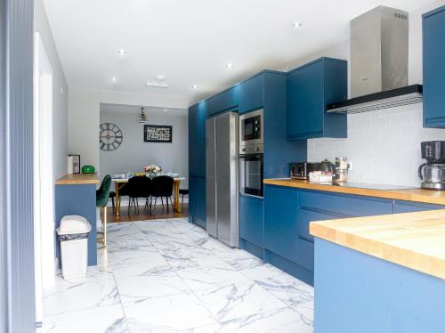 a kitchen with blue cabinets and a dining room at Royal Luxe 4 - 6 Bed House in London in Bexleyheath