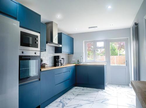 a blue kitchen with blue cabinets and a window at Royal Luxe 4 - 6 Bed House in London in Bexleyheath