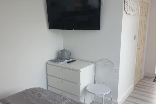 a white dresser with a chair and a tv on a wall at Near liverpool double bedroom hideaway in Wirral
