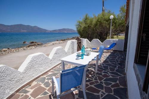 a table and chairs on a patio next to the beach at Cottage On The Wave With Amazing View in Paralia Kallonis