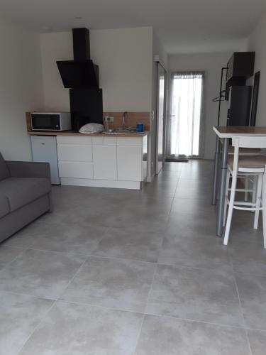 une cuisine et un salon avec un canapé et une table dans l'établissement Les Pivoines studio climatisé, proximité mer et forêt, à Saint-Hilaire-de-Riez