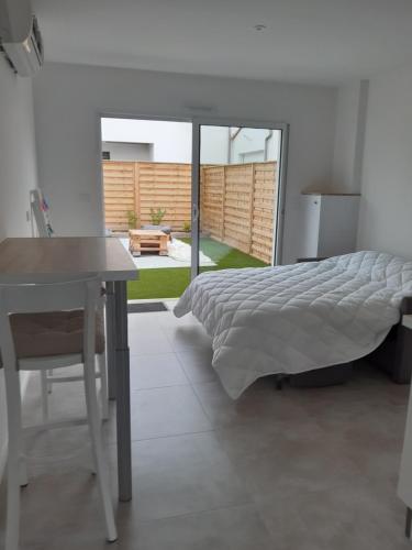 une chambre avec un lit, une table et un bureau dans l'établissement Les Pivoines studio climatisé, proximité mer et forêt, à Saint-Hilaire-de-Riez