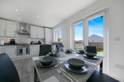 a kitchen with a table with plates and wine glasses at Clapham Wynd House - Grampian Lettings Ltd in Arbroath