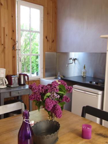 une cuisine avec une table et un vase de fleurs violettes dans l'établissement Maison de campagne au bord de la mer, à Fort-Mahon-Plage