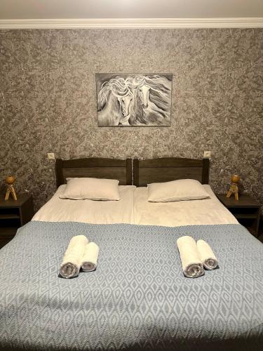 a bedroom with a bed with two pairs of slippers at Apartment Nikolo in Kazbegi