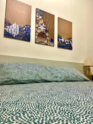 1 dormitorio con 4 pinturas en la pared en Ciauru di Casa, en Portopalo di Capo Passero