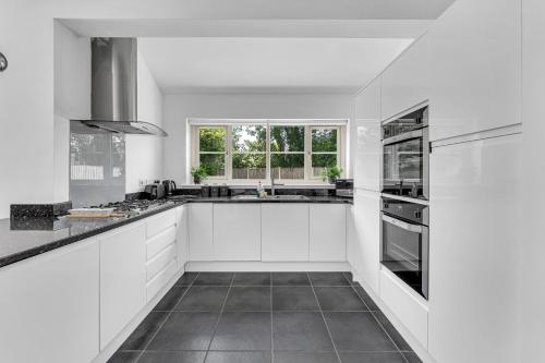 a white kitchen with white cabinets and a window at Brook Meadow House, 4 bed house, Manchester in Astley