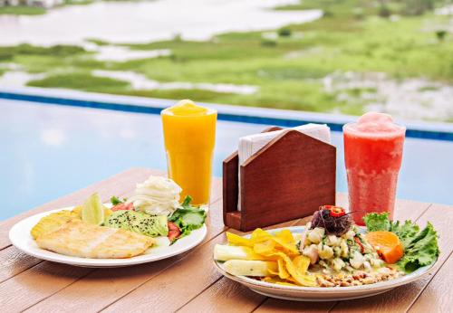 a table with two plates of food and two drinks at Hotel de Turistas Iquitos in Iquitos