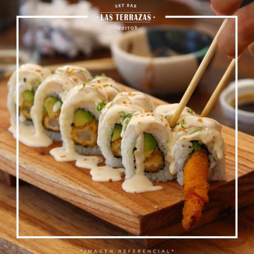 a group of sushi on a cutting board with a person holding a plate at Hotel de Turistas Iquitos in Iquitos