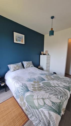 une chambre avec un grand lit avec un mur bleu dans l'établissement Appartement lumineux dans résidence calme et arborée, à Cabourg