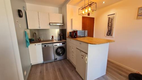 une cuisine avec un comptoir et un lave-linge/sèche-linge dans l'établissement Appartement lumineux dans résidence calme et arborée, à Cabourg