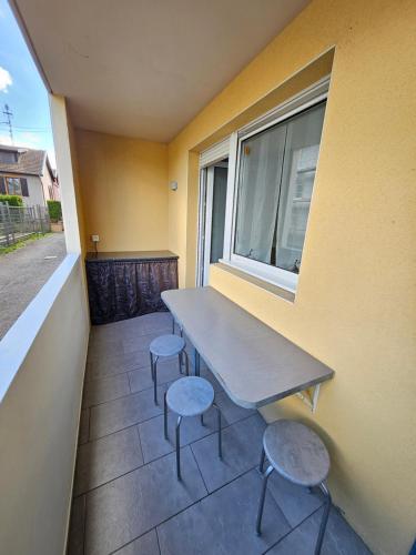 a table and stools on a balcony with a window at F3 rez-de-chaussée Centre ville au calme avec Balcon Garage et Netflix in Héricourt