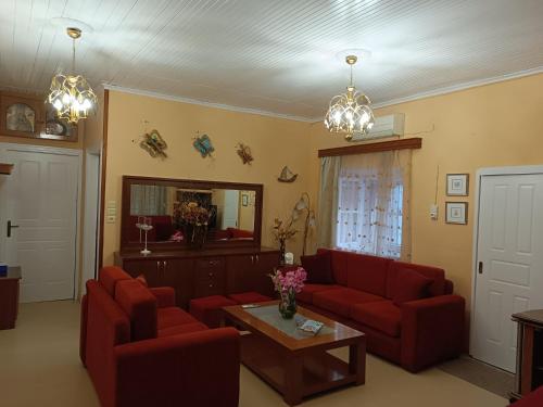 a living room with red couches and a table at Rodomelo House with Terrace - 4 Bedrooms in Leonidion