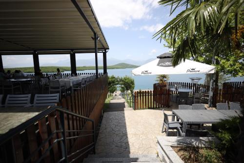 - un restaurant avec des tables, un parasol et l'océan dans l'établissement Hotel Liqeni i Dukagjinit, à Gjakove