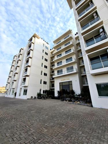 two large white apartment buildings next to a brick street at Free Parking-Luxury 1 Bed with Pool,Gym,Cinema in Lahore
