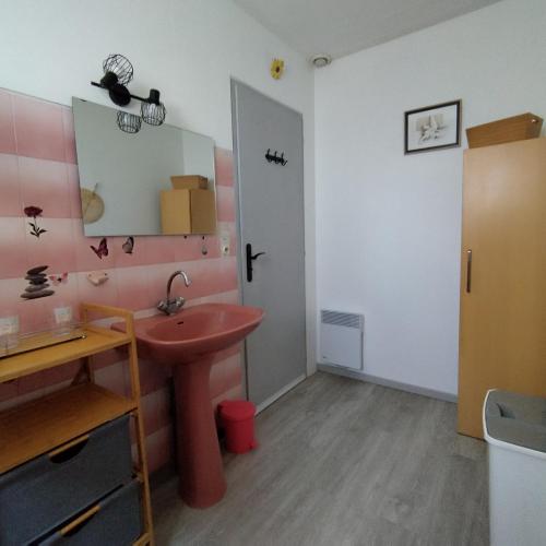 La salle de bains est pourvue d'un lavabo rouge et d'un miroir. dans l'établissement maison la garenne, à Royan