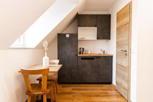 a kitchen with a wooden table and a kitchen under the stairs at Pension Märkl Augsburg in Augsburg